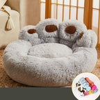 Fluffy gray pet bed with brown accents on a beige couch.