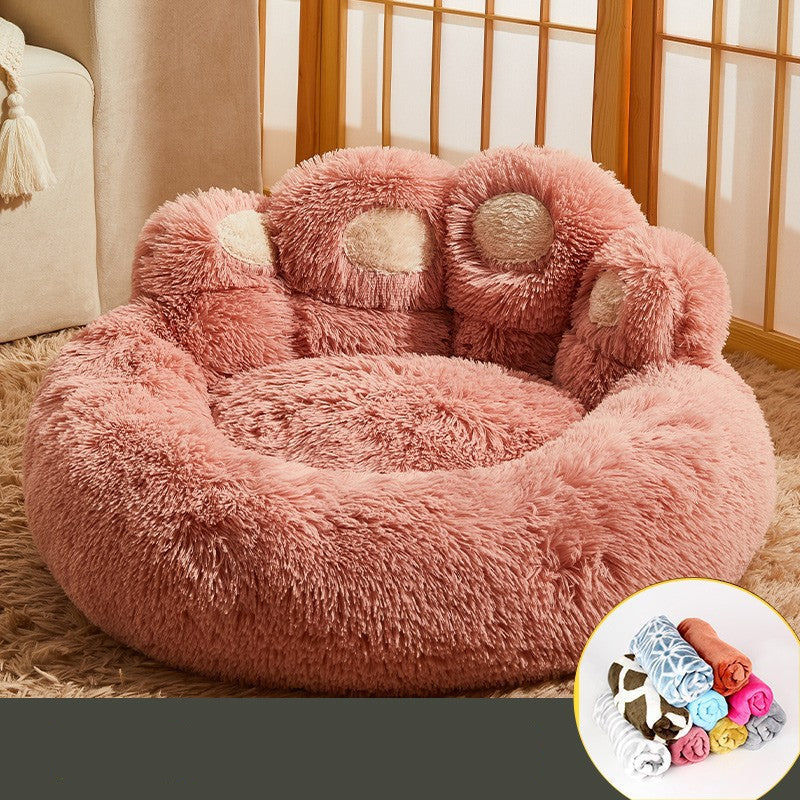Fluffy pink paw-shaped pet bed on a carpeted floor with a window in the background.