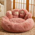Fluffy pink pet bed with paw design on a carpeted floor.