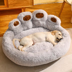 Dog lying on a fluffy paw-shaped pet bed in a room with wooden flooring.